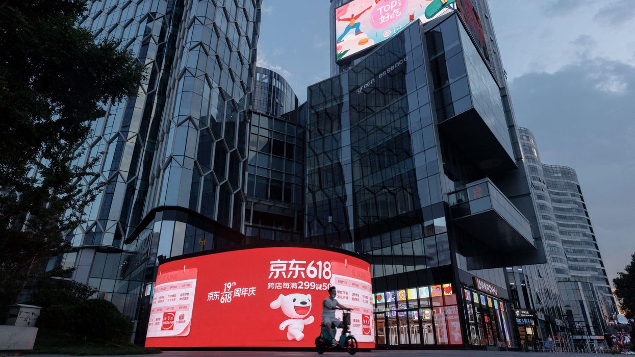 ​A person rides a scooter past a JD.com advertisement for the "618" shopping festival