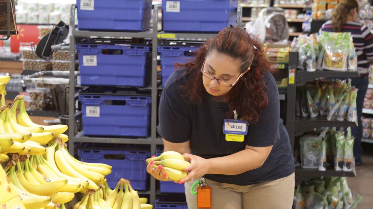 A Walmart worker looking at bananas.