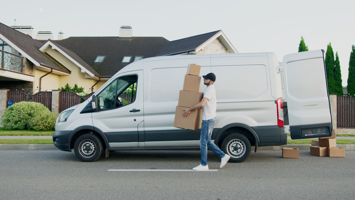 man carrying boxes in front of a white van